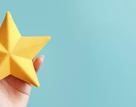 Image shows a hand holding a foam, yellow star.
