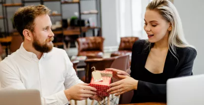 Image shows one employee giving a gift to another employee.